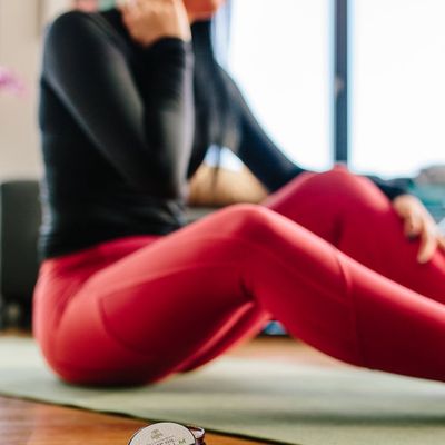 A simple water bottle and a rolled-up exercise mat on a wooden floor.